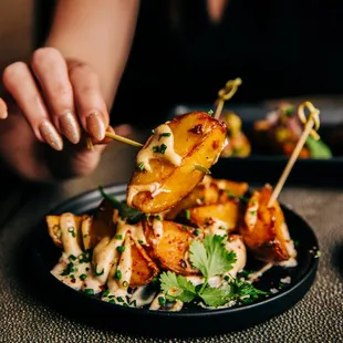 a person holding a toothpick over a plate of food
