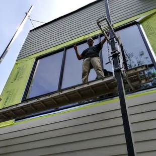 a man on a ladder working on a house