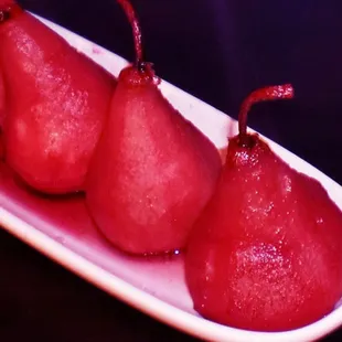 three red pears on a white plate