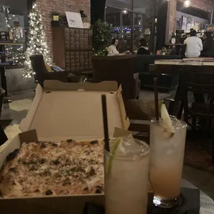 a pizza in a box and a drink in a glass