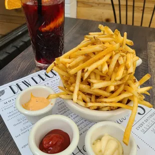 a bowl of french fries with ketchup and condiments