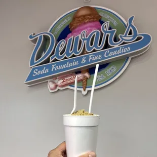 a hand holding a cup of ice cream