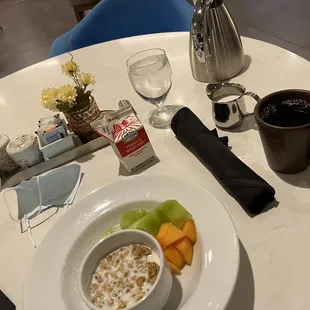 a bowl of oatmeal, a cup of coffee, a cantaloupe, and