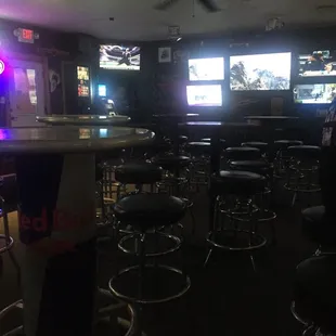 a bar with stools and televisions