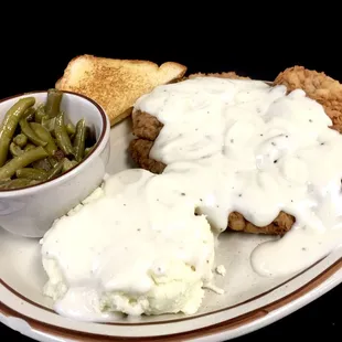 a plate of fried chicken with gravy and green beans