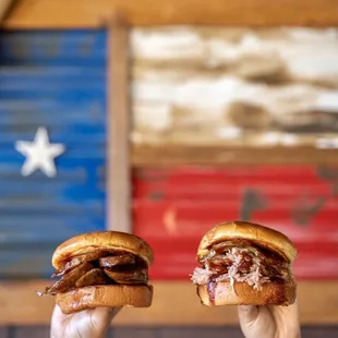 two hands holding two sandwiches