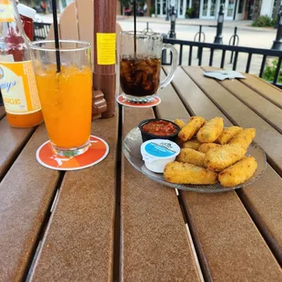 a plate of fried donuts and a glass of orange juice