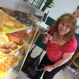 a woman standing in front of a display case of doughnuts