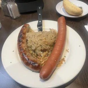Bratwurst, Sauerkraut, and Knockwurst. Long shaped bread is roll brought to table with plates.