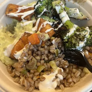 a bowl of food with rice, broccoli, carrots, and other vegetables