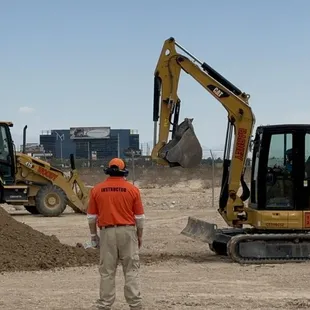 Patrick giving instruction via headset. He carries a remote control kill switch to stop the excavator if needed.