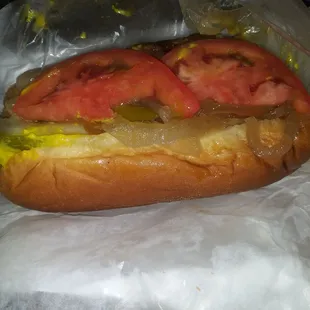 a hot dog with tomatoes and pickles