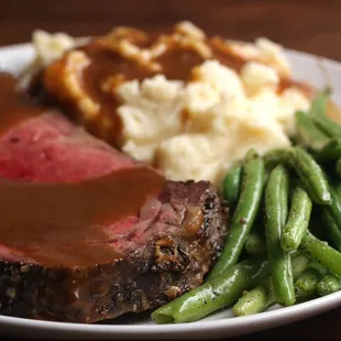a plate of meat with gravy and green beans