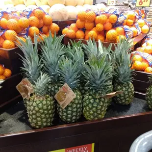 a display of pineapples and oranges