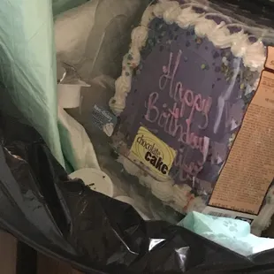 a birthday cake in a garbage can