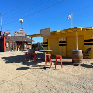 tables and chairs in front of a yellow building