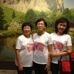 three asian women standing in front of a mountain backdrop
