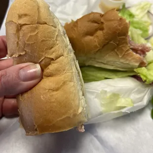 Italian sub being held for size scale=cheap hot dog bun