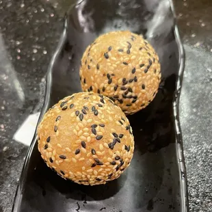 two sesame buns on a black plate