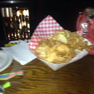 a wooden table with a basket of french fries and a glass of red wine