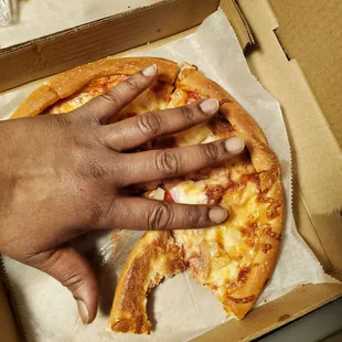 a hand reaching for a slice of pizza