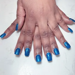 a woman&apos;s hands with blue nail polish