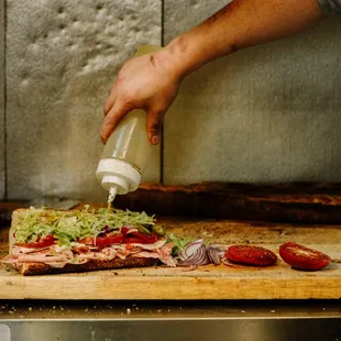 a person putting sauce on a pizza