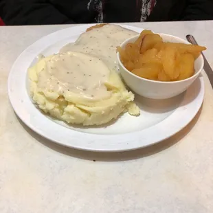 a plate of mashed potatoes, gravy and a bowl of fruit