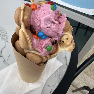 Strawberry ice cream on bubble waffle with m&amp;m toppings.