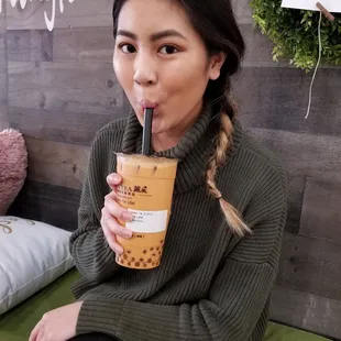 a woman sitting on a bed drinking a drink