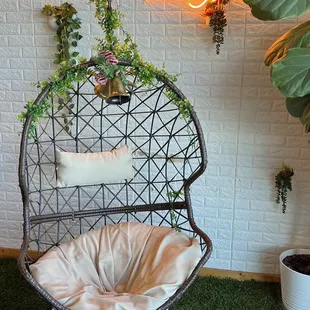 a hanging chair with plants and a neon sign