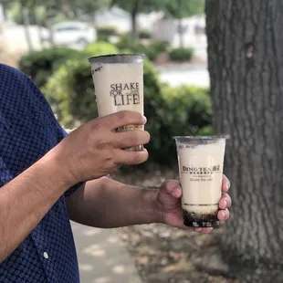 a man holding two cups of coffee