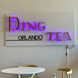 a table and chairs in front of a neon sign