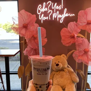 a person holding a cup of coffee and a teddy bear