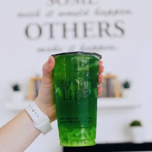 a hand holding a green drink