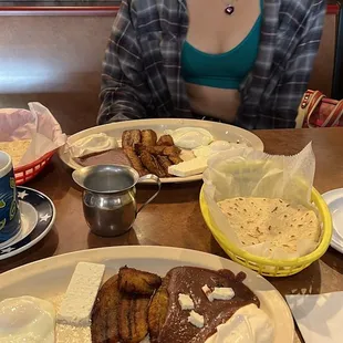 a woman sitting at a table with plates of food