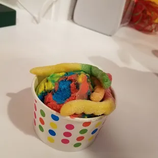 A single scoop of Superman with gummy worms on top.