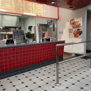 a restaurant counter with a menu on the wall