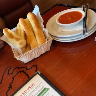 a basket of breadsticks and a bowl of tomato soup