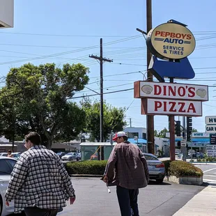 Corner sign of Dino&apos;s Pizza, shared with Pep Boys, along with their parking lot