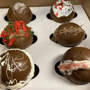 six chocolate covered pastries in a box