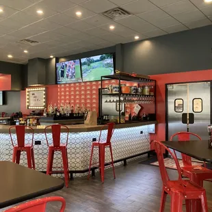 a restaurant with red chairs and a bar