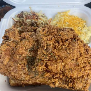 Pork chop meal with grits and hash browns for sides.