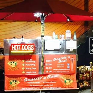 a hot dog stand with a red umbrella