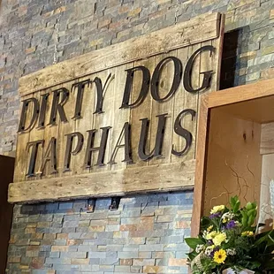 a vase of flowers in front of a dirty dog taphaushaus sign