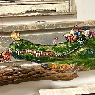 Gator and Butterflies painted on a reclaimed door with driftwood from the Mississippi River. Original by local artist, Paige DeBell.