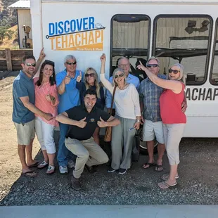 Tour customers posing with tour guide at Tehachapi Winery in front of a tour bus.