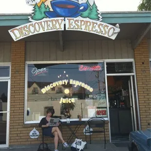 a man sitting on a bench in front of a coffee shop