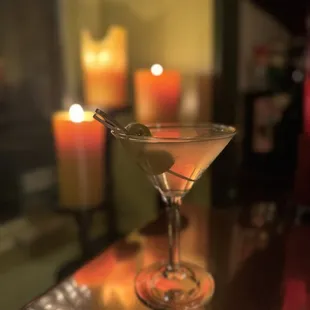 a martini on a bar with candles in the background
