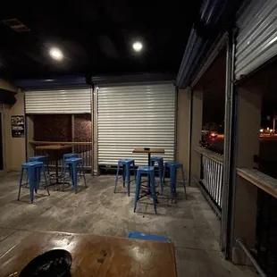 a dark room with blue stools and tables